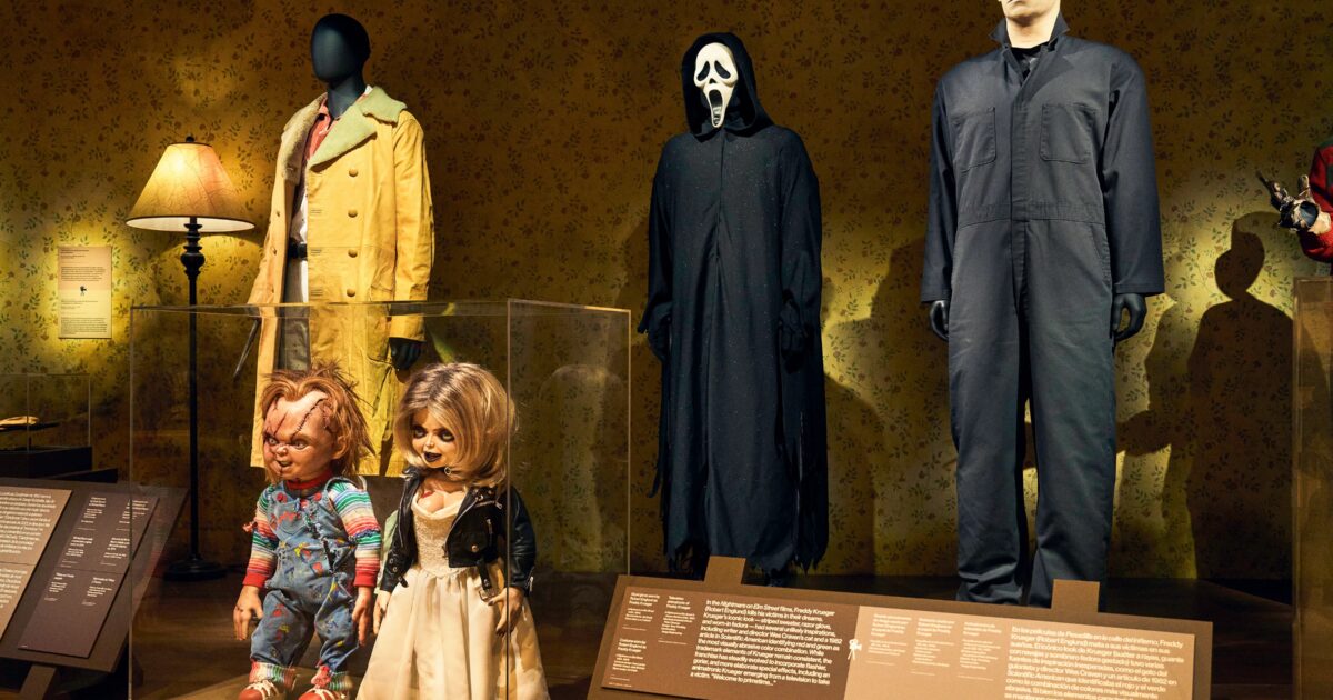 Vetrina museale con costume horror maschera e poster di film classici Gamescafe Vetrina museale con costume horror maschera e poster di film classici