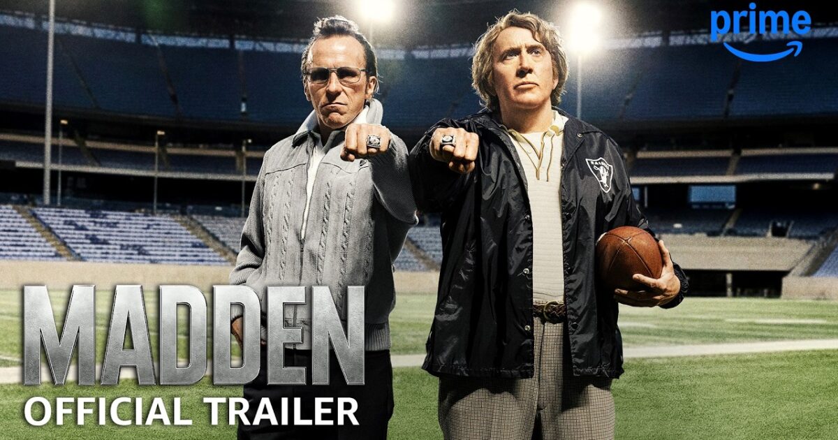 Nicolas Cage nei panni di John Madden davanti a uno sfondo NFL Gamescafe Nicolas Cage nei panni di John Madden davanti a uno sfondo NFL