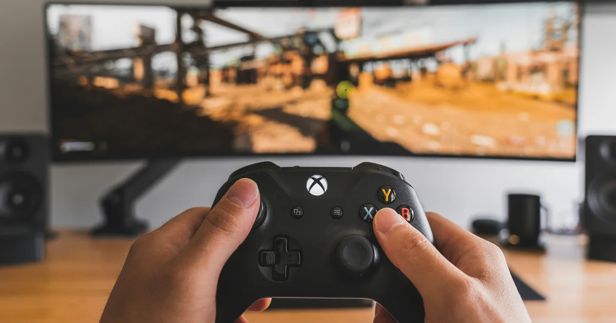 Controller Xbox davanti a un monitor Gamescafe Mani su un controller Xbox davanti a un monitor con un videogioco