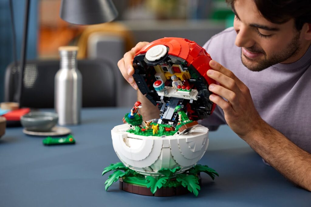 Un uomo apre una Poké Ball LEGO con un piccolo scenario Pokémon e minifigure al suo interno