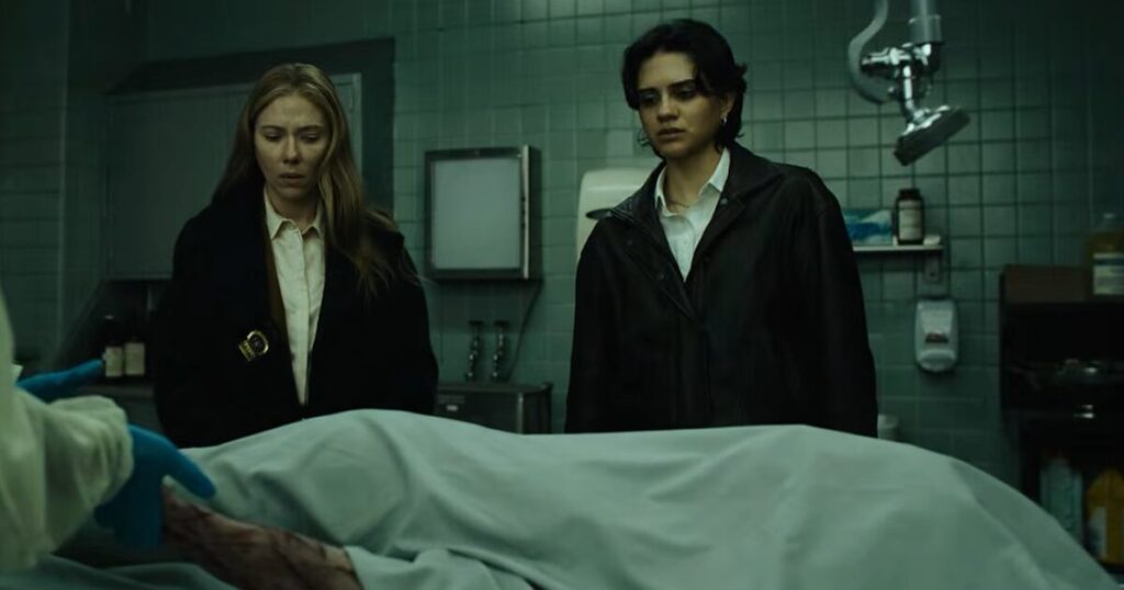 Scarlett Johansson in abiti da detective davanti a una scena del crimine cupa e religiosa