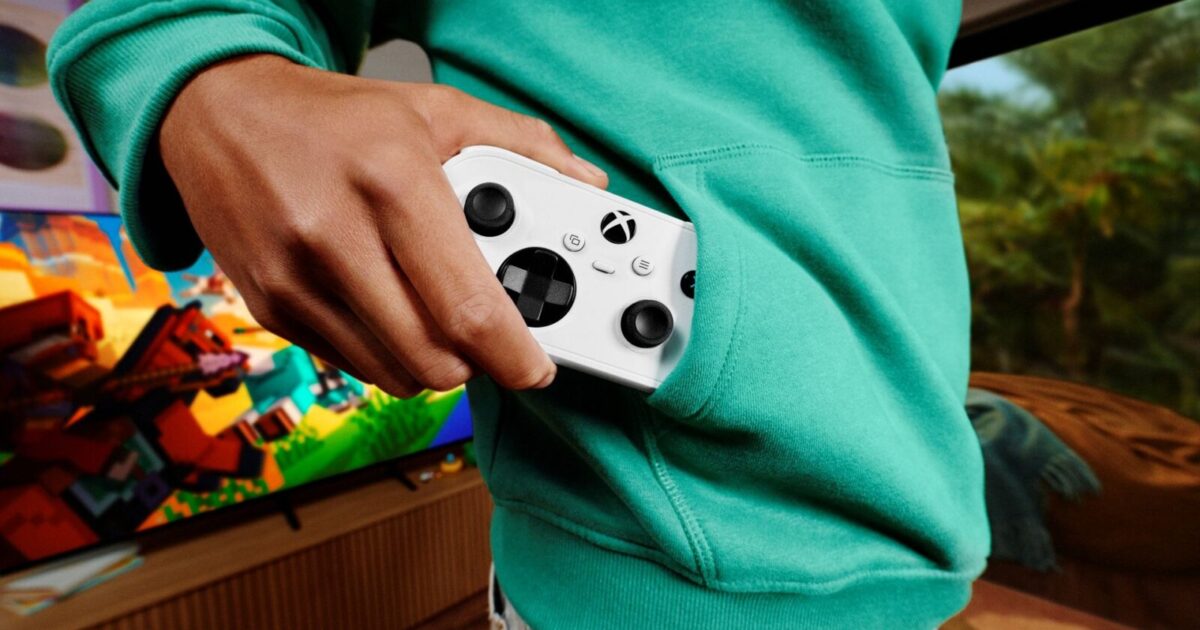 Xbox Nano Controller immagine ufficiale Xbox Gamescafe Una persona infila il controller bianco Xbox Nano nella tasca di una felpa verde